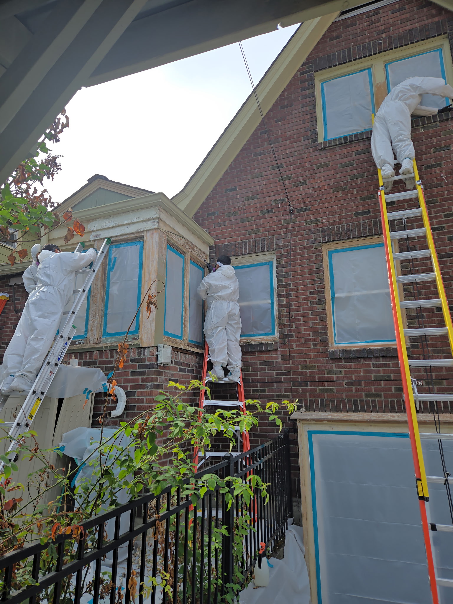 Abatement crew in protective suits on building exterior